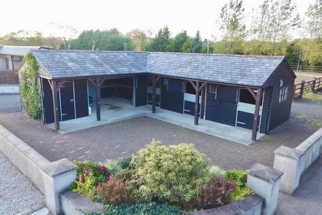 Features of the property include multiple stables and a floodlit sand arena