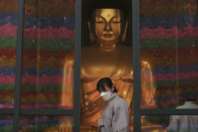 A Buddhist believer wearing a face mask leaves the Jogyesa Buddhist temple in Seoul, South Korea, Tuesday, Feb. 25, 2020