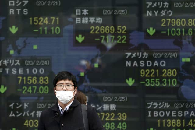 A man stands in front of an electronic stock board showing Japan's Nikkei 225 index and other city's index at a securities firm in Tokyo Tuesday, Feb. 25, 2020