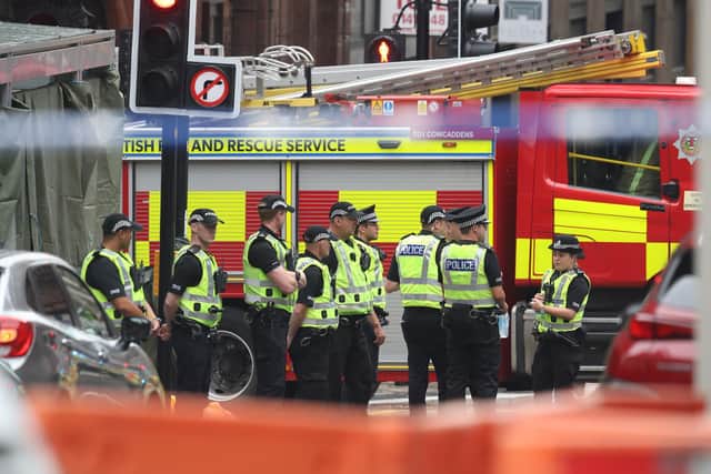 Police officers stand by a screen which has been erected at the scene in West George Street, Glasgow, where a man has been shot by an armed officer after another officer was injured during an attack. (Photo: PA Wire)