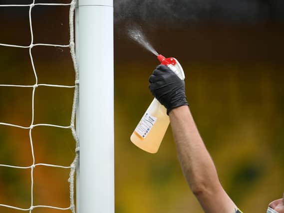 Staff spray disinfectant on the goal