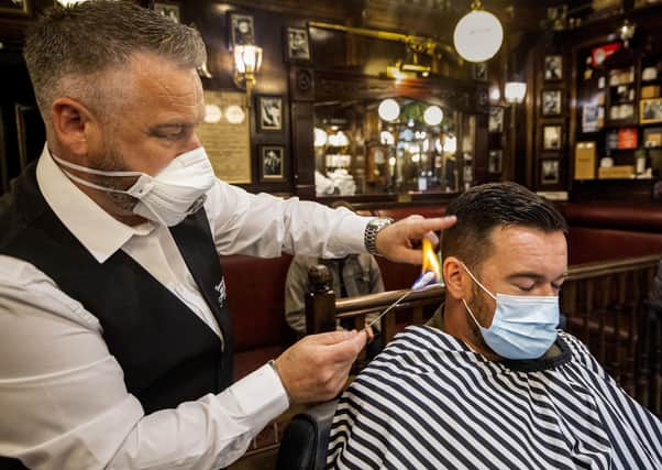 Sean Lawlor (left) singeing the hair of Damian Gilvary (right) during a haircut at Cambridge Barbershop on Belfast's Lisburn Road. Photo: Liam McBurney/PA Wire