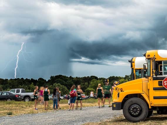 Lightning fills the sky as students wait by the bus at Shamrock Farms in Rockingham County, Va., on Wednesday, Sept. 9, 2015. The District Valley cross country meet was called off because of the weather. (Austin Bachand/Daily News-Record via AP)