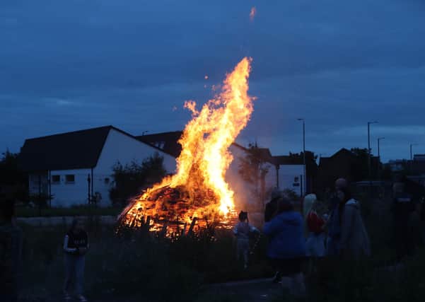 A number of people watch a bonfire on Belfast's Shankill Road as bonfires were set to be lit at midnight. Photo: Niall Carson/PA Wire