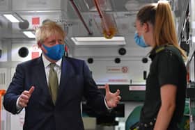 Prime Minister Boris Johnson, wearing a face mask, talks with a paramedic during his visit to the headquarters of the London Ambulance Service NHS Trust