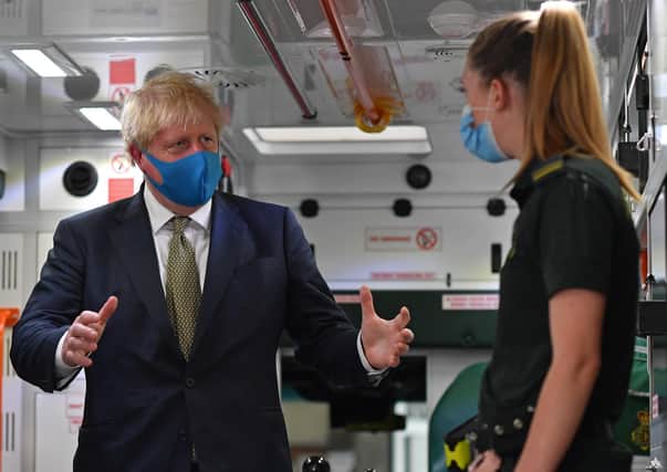 Prime Minister Boris Johnson, wearing a face mask, talks with a paramedic during his visit to the headquarters of the London Ambulance Service NHS Trust