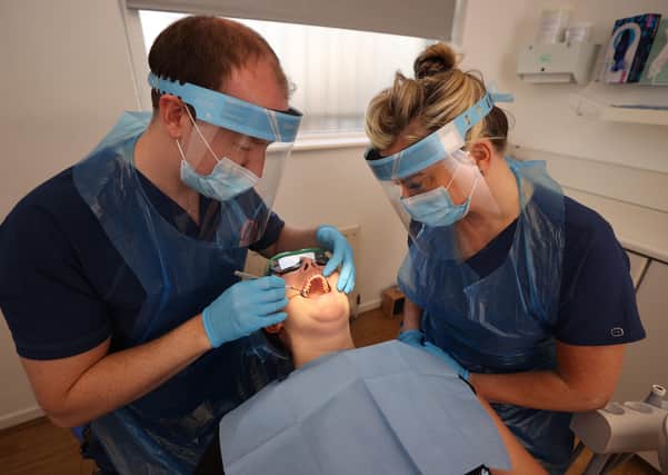 Dentist Dr Alan Clarke and Dental Nurse Lynsey Galaway (right) wearing PPE with fellow dentist Dr Danielle Magee in the chair in Belfast on Monday