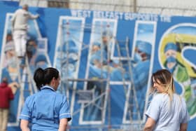 A nurse watches on as an ‘NHS’ mural is painted on the Falls Road in Belfast