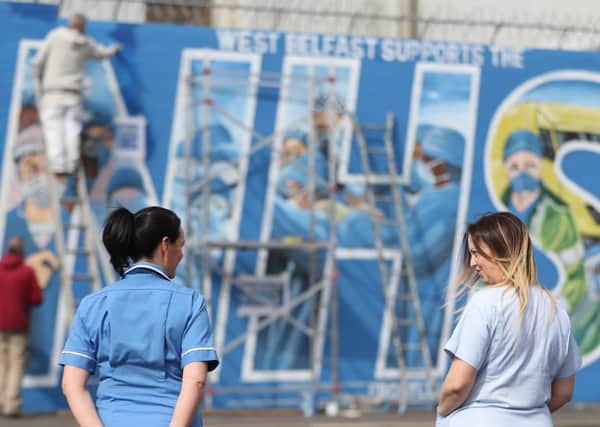 A nurse watches on as an ‘NHS’ mural is painted on the Falls Road in Belfast