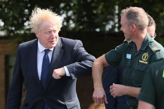 Prime Minister Boris Johnson elbow bumps a paramedic at the Northern Ireland Ambulance Service HQ during a photo op on Thursday