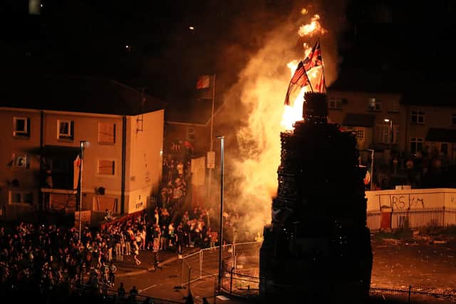 Flags including the Union and US flag at burnt at the top of a giant bonfire in the Bogside area on Saturday. Photo: Brian Lawless/PA Wire