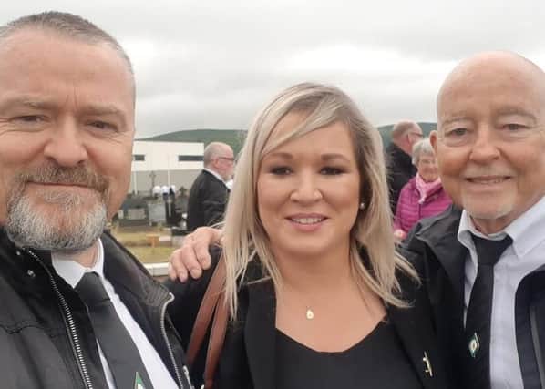 Michelle O’Neill pictured having her photo taken with fellow mourners at Bobby Storey’s funeral, with a crowd gathered behind her