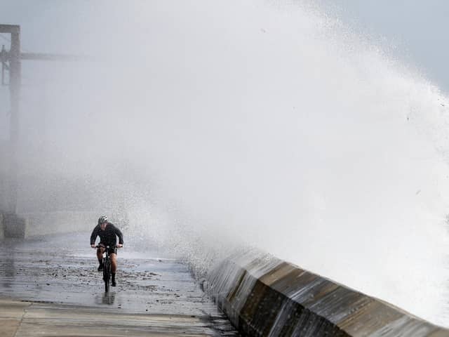A cyclist is hit by a wave as he cycles along the shoreline in Saltcoats on the west coast of North Ayrshire as gusts of up to 70mph could hit coastal areas as Storm Ellen moves on and leaves more wet and windy weather in its wake.