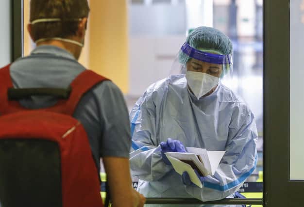 A medical worker wearing protective gear delivers a report of a COVID-19 test to a passenger of a flight from Valencia, Spain, at Rome's Ciampino airport. (AP Photo/Riccardo De Luca)