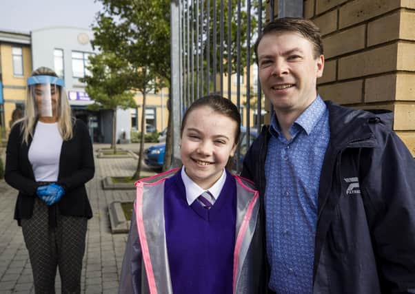 Brendan Gallagher dropping off his 11 year old daughter Abigail at St Clare's Primary School in Belfast with teacher Ashleigh Clarke greeting them wearing a protective visor and gloves, as primary 7 year pupils are allowed to return to school inn Northern Ireland. PA Photo.