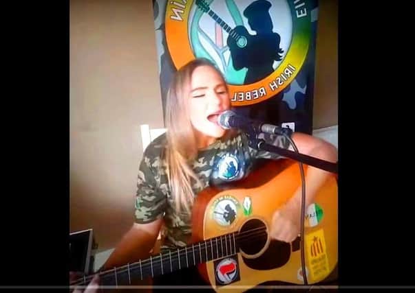 Eimhear Rebel in branded camouflage attire singing Sean South of Garryowen (about a Border Campaign-era IRA man). Her guitar also bears the emblem of the leftist organisation known as Antifa