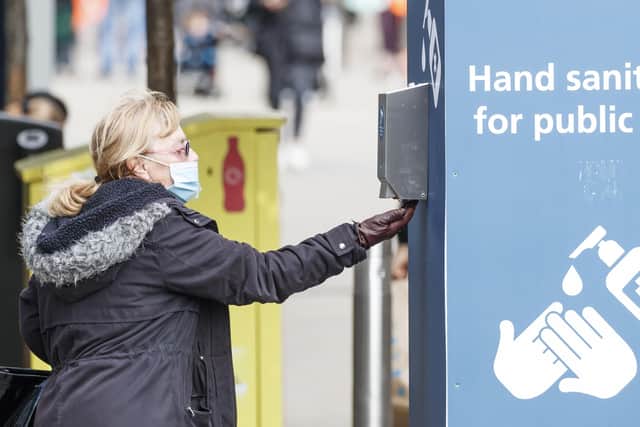 A woman uses a public hand sanitiser