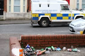 A police patrol drives past a host of discarded beer tins and bottles in a front garden of a Holylands house on Wednesday