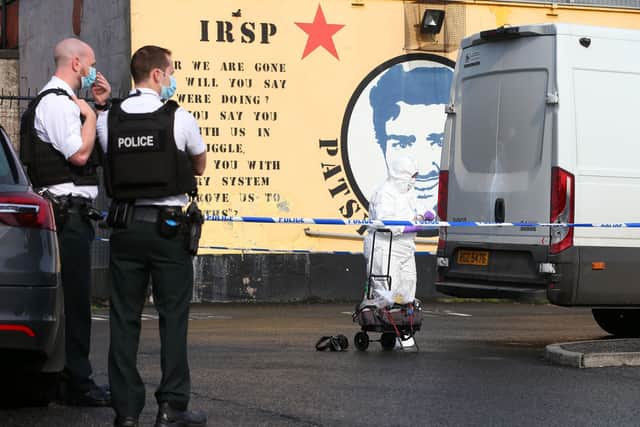 PSNI officers and forensic officers at the scene of a cigarette robbery in west Belfast this morning.