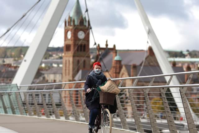 A woman cycles across the Peace Bridge over the River Foyle in Derry. The Stormont Executive announced a wide-ranging series of restrictions for the Derry City and Strabane Council area on Thursday in an effort to stem the spiralling Covid-19 infection numbers in the north-west of Northern Ireland.