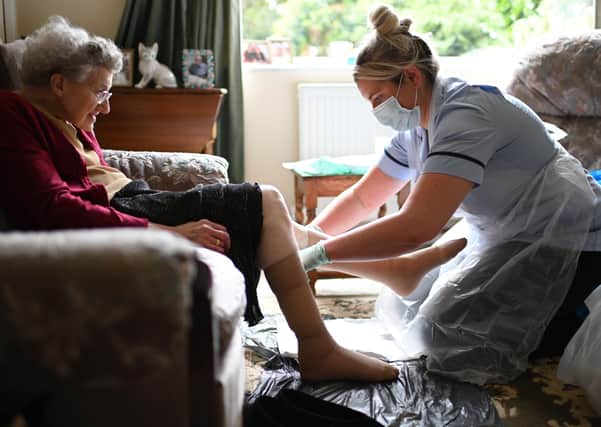 File photo dated 09/06/20 a nurse Rebecca, wearing personal protective equipment (PPE), changes the dressings on the legs of an elderly woman.