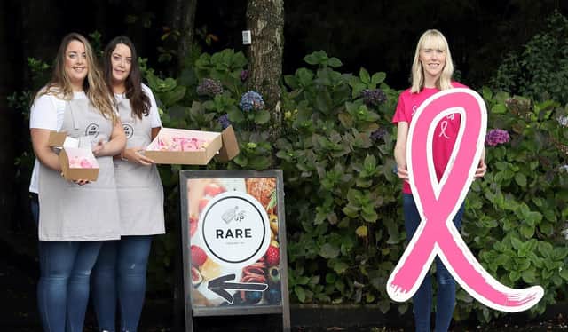 Twins Rachel and Rebecca Vance tempt Maeve Colgan, from Cancer Focus NI, with their pretty pink graze box which will help raise funds for breast cancer patients during October, breast cancer awareness month