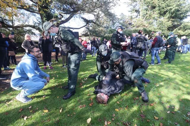 Police officers detain an anti-lockdown protester on the Stormont estate in Belfast