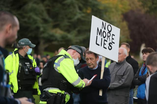 A police officer hands out an on the spot fine to a protester on the Stormont estate in Belfast