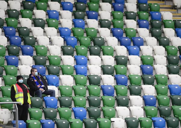 A Linfield fan and a steward surrounded by empty seats in Windsor Park at the Linfield v Carrick clash last  Saturday