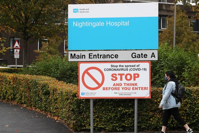 A woman wearing a face mask walks past an entrance to Belfast City Hospital.
