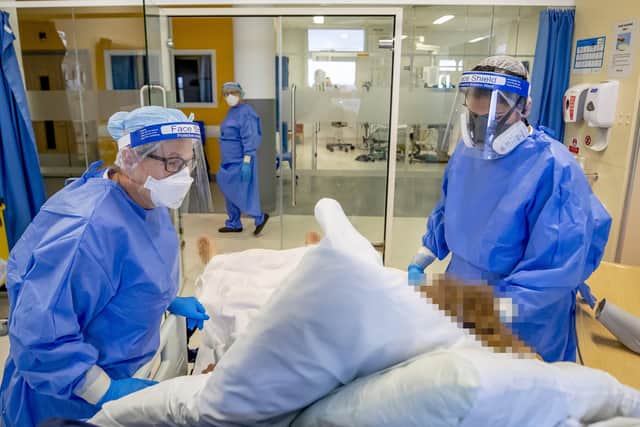 Health workers wearing full personal protective equipment (PPE) tend to a patient on the intensive care unit (ICU).
