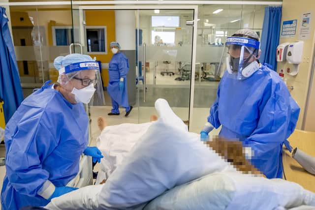 Health workers wearing full personal protective equipment (PPE) tend to a patient on an intensive care unit (ICU).