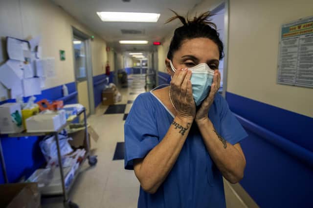 Nurse Cristina Settembrese fixes two masks to her face during her work shift in the COVID-19 ward at the San Paolo hospital in Milan, Italy, Friday