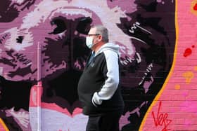 A man wearing a facemark, due to COVID-19 restrictions, walks past some art work on Pottinger's Entry in Belfast City Centre