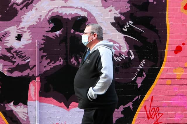 A man wearing a facemark, due to COVID-19 restrictions, walks past some art work on Pottinger's Entry in Belfast City Centre