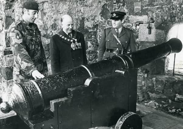 The Mayor of Carrickfergus, Alderman Hugh McClean looks over the cannon which was flown in to the castle by military helicopter in October 1977. He is pictured with Sergeant George Turner (74) (AA) Engineers, left, and Lieutenant S Wilson 114 Field Squadron. Picture: News Letter archives