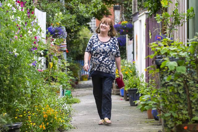 Brid Ruddy is chair of Holyland Residents’ Network. She is seen here in 'Wildflower Alley' after residents campaigned to have gates on the alleyway to increase community safety and put a stop the anti-social behaviour the alleyway attracted. The alleyway has been designed with flowers, places to sit and has used recycled goods to build it