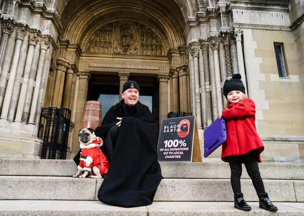 The Dean of St Anne's Cathedral Belfast launching his annual Black Santa stand out with Rowan Wylie who is making her donation online. Picture: Elaine Hill