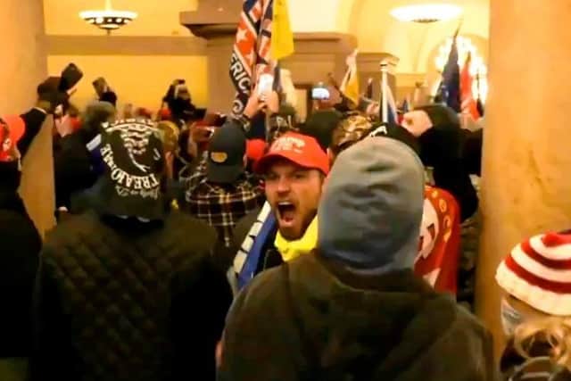 A man in a Trump baseball cap screams 'Stop the Steal' as protestors flood into the building's ornate atrium