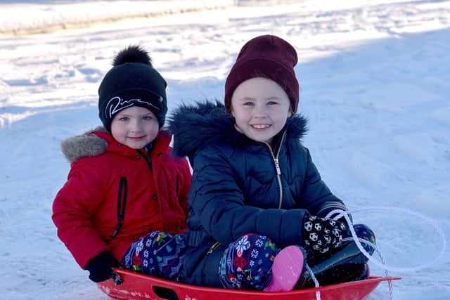 Pheo, aged 5, and Katie Mooney (7) enjoy the snow at the Creggan Burn. Photo: George Sweeney / Derry Journal.  DER2104GS – 012