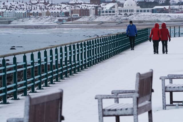 People take a walk in snow that has fallen overnight