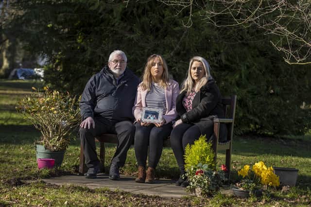 Lisa Dorrian’s father John and her sisters Michelle (centre) and Joanne (right) sitting at a memorial bench to Lisa at Castle Park in Bangor beside a cherry blossom tree planted by her friends 16 years ago