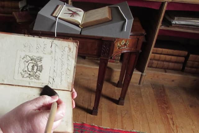 Cleaning one of the books at Florence Court
