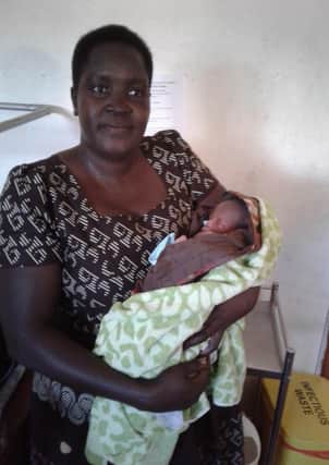 Self Help Africa's Esther Ainyo with a baby she helped deliver when a woman went into labour during a training course she was giving