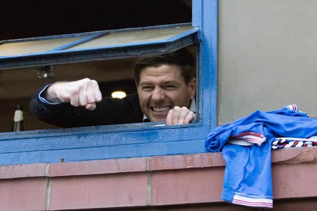 Rangers manager Steven Gerrard hangs out the window of the dressing room to cheer with fans gathered outside Ibrox stadium after the Scottish Premiership match with St Mirren