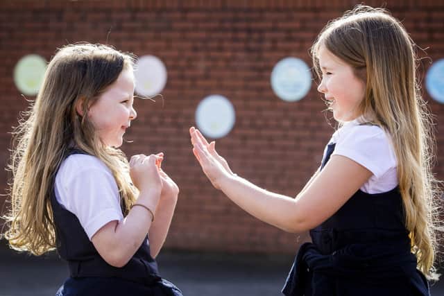 P3 children Scarlett Greggan (left) and Madison Lowry playing patty cake during their lunch break in the playground of Springfield Primary School in Belfast