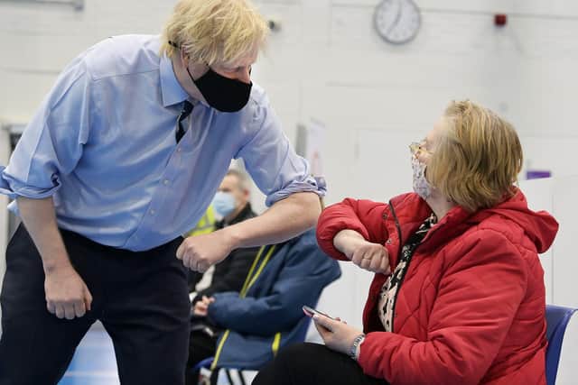 Prime Minister Boris Johnson elbow bumps a member of the public as they wait to be vaccinated during a visit to the Lakeland Forum vaccination centre in Enniskillen.