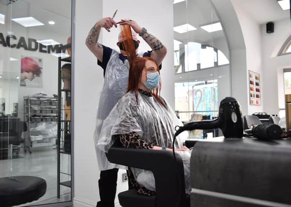Senior stylist Robert Brooks cuts the hair of Carmen Smith at the Lazarou salon in Cardiff, Wales. Hairdressers and barbers in Wales reopened last month. Picture date: Monday March 15, 2021.