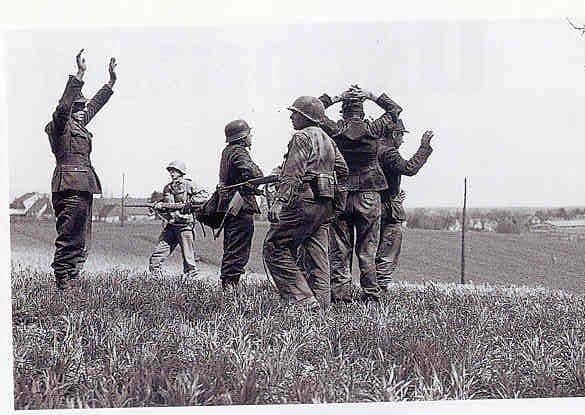 Teddy Dixon - centre with gun pointed at surrendering SS camp guard on the approach to Dachau concentration camp