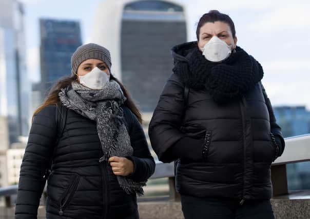 People wearing a protective face masks, walk across London Bridge as Britain braces itself for an increase in cases of the Coronavirus. Photo: TOLGA AKMEN/AFP via Getty Images.